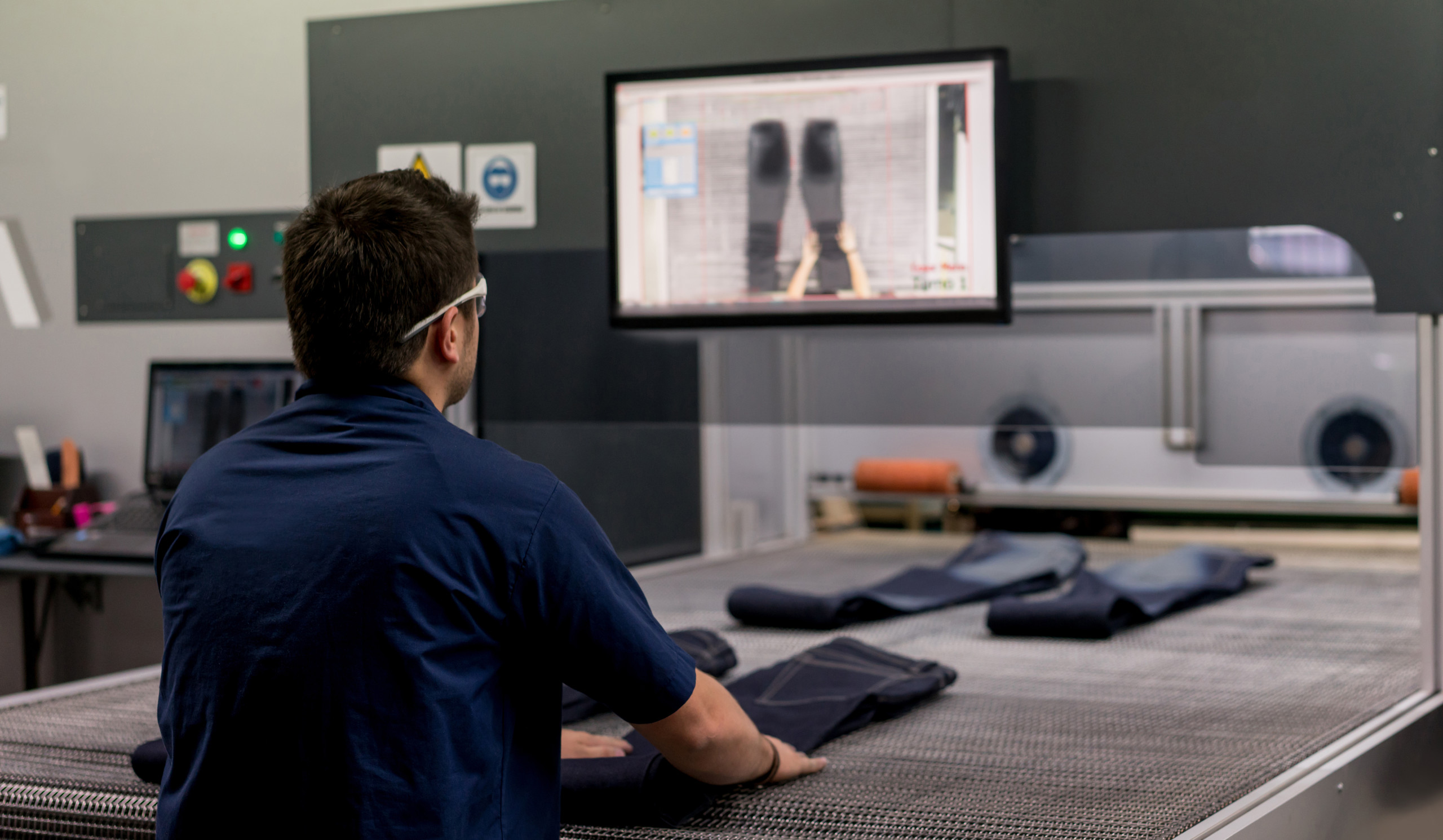 Man operates laser machine in the denim production 